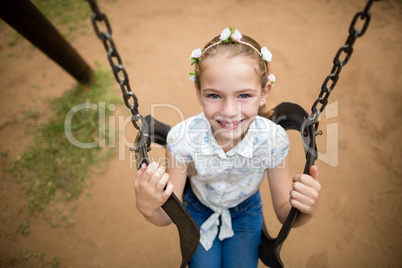 Happy girl sitting on a swing in park