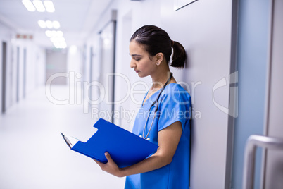 Female doctor reading reports in corridor