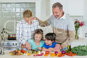 Smiling parents and children chopping vegetable in kitchen