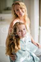 Smiling mother and daughter in towel at bathroom