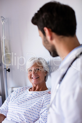 Male doctor consoling female senior patient