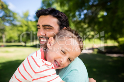Son smiling while embracing his father in park