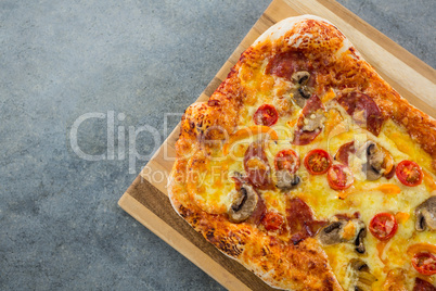 Pizza served in a chopping board on a wooden plank