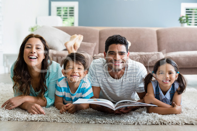 Portrait of parents and children lying on rug and reading book