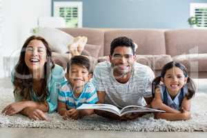 Portrait of parents and children lying on rug and reading book