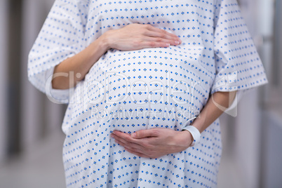 Mid section of pregnant woman standing in corridor