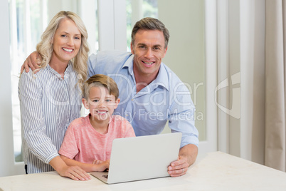 Parents and son using laptop at home