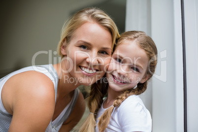 Smiling mother and daughter standing at home