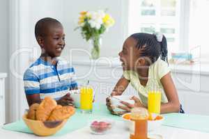 Siblings having breakfast on dining table at home