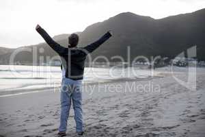 Mature man standing with arms outstretched on the beach