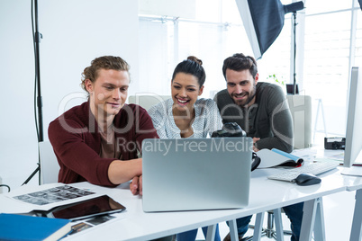 Team of photographers working over laptop at desk