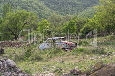 Old rusty car in the meadow