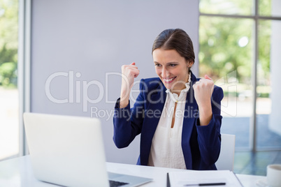 Happy businesswoman using laptop at desk