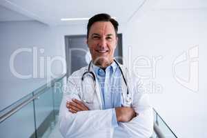 Male doctor smiling and standing with arms crossed