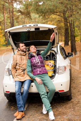 Smiling couple sitting in car trunk