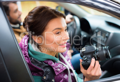 Smiling woman holding camera in car