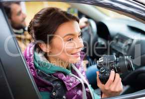 Smiling woman holding camera in car