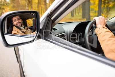 Smiling driver reflected in car mirror