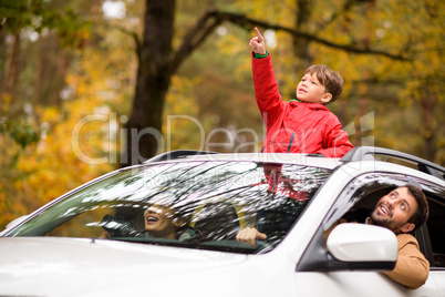 Adorable boy standing in car sunroof