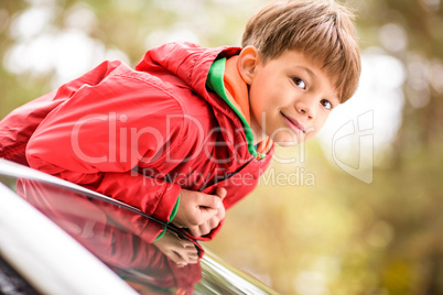 Cute little boy standing in car