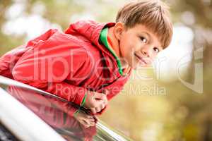 Cute little boy standing in car
