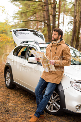 Man holding map and leaning on car