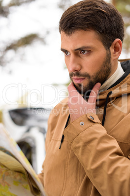 Bearded man holding map in forest