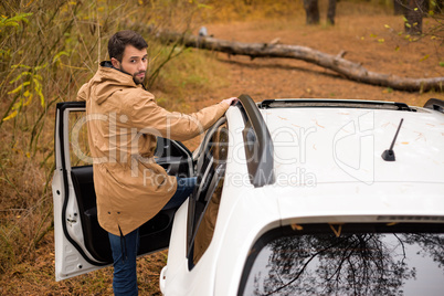 Man standing near car and fallen tree