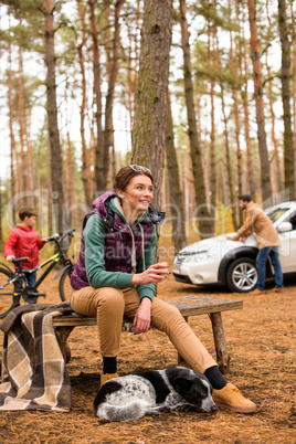 Smiling woman with hot drink in forest