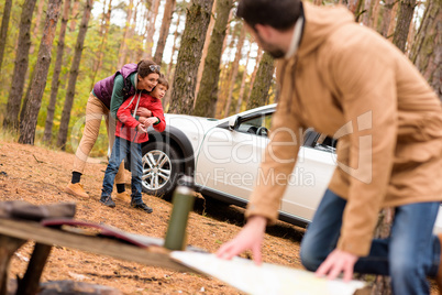 Woman with boy standing near car in forest