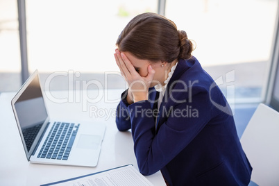 Tired businesswoman sitting at desk with laptop