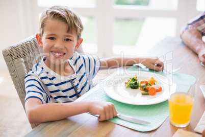 Cute boy having meal on dinning table