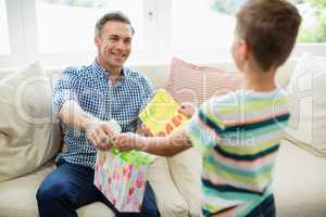 Father receiving a gift from his son in living room