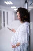 Pregnant woman using mobile phone in corridor