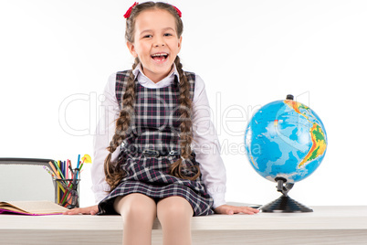Happy schoolgirl sitting  with globe