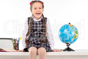Happy schoolgirl sitting  with globe