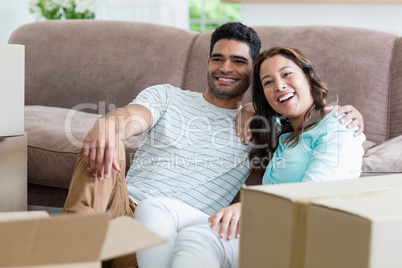 Happy couple sitting with arm around in living room