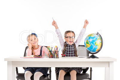 Happy schoolgirls sitting with globe