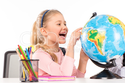 Happy schoolgirl exploring globe