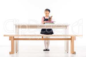 Serious schoolgirl standing at desk