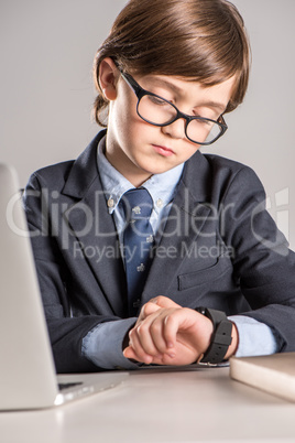 Schoolchild in business suit looking at smartwatch