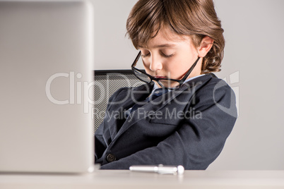 schoolchild in business suit sleeping near laptop