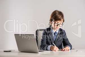 Schoolchild in business suit writing documents