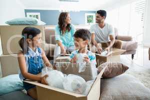 Parents and kids unpacking carton boxes in living room
