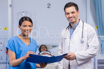 Portrait of smiling nurse and doctor holding clipboard