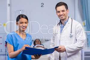 Portrait of smiling nurse and doctor holding clipboard