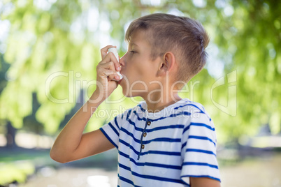 Boy using asthma inhaler in park