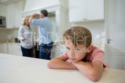 Sad boy listening to his parents arguing