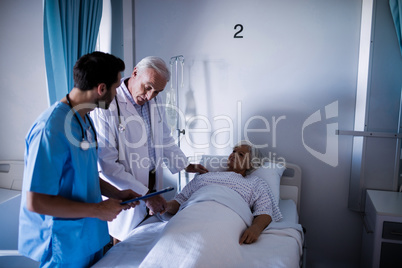 Doctors comforting senior patient on bed