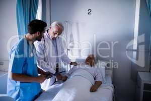 Doctors comforting senior patient on bed